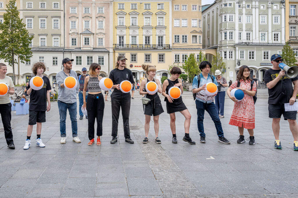 photograph of performance showing 10 people holding painted beach balls to display the data