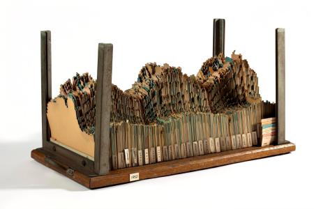 Photograph of "Electricity generated or demanded in Manchester, 1951–1954." This type of visualization is known as a "load model", which represents power consumption in three dimensions. Each day is represented as a piece of cardboard, with the top edge of the cardboard cut away to form a column chart with the height of each column representing electricity demand over 30 minutes. The daily cards are stacked tightly together, so the tops create a 3-dimensional surface that indicates power usage over several years.
