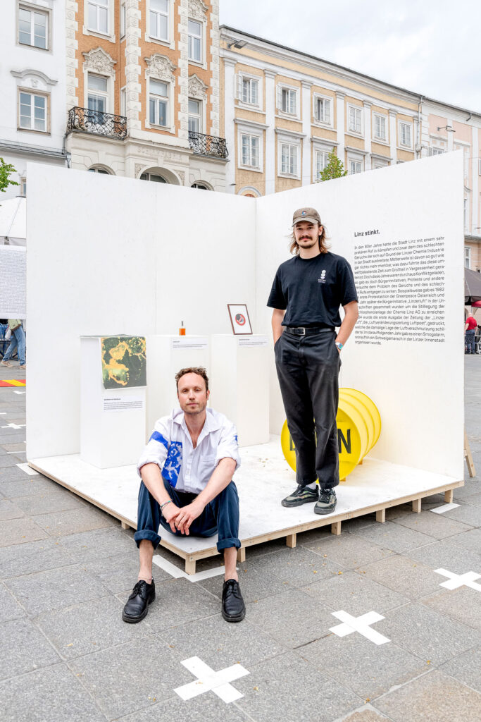 2 students pose with their exhibit that recreates an industrial smell that used to be frequent in Linz