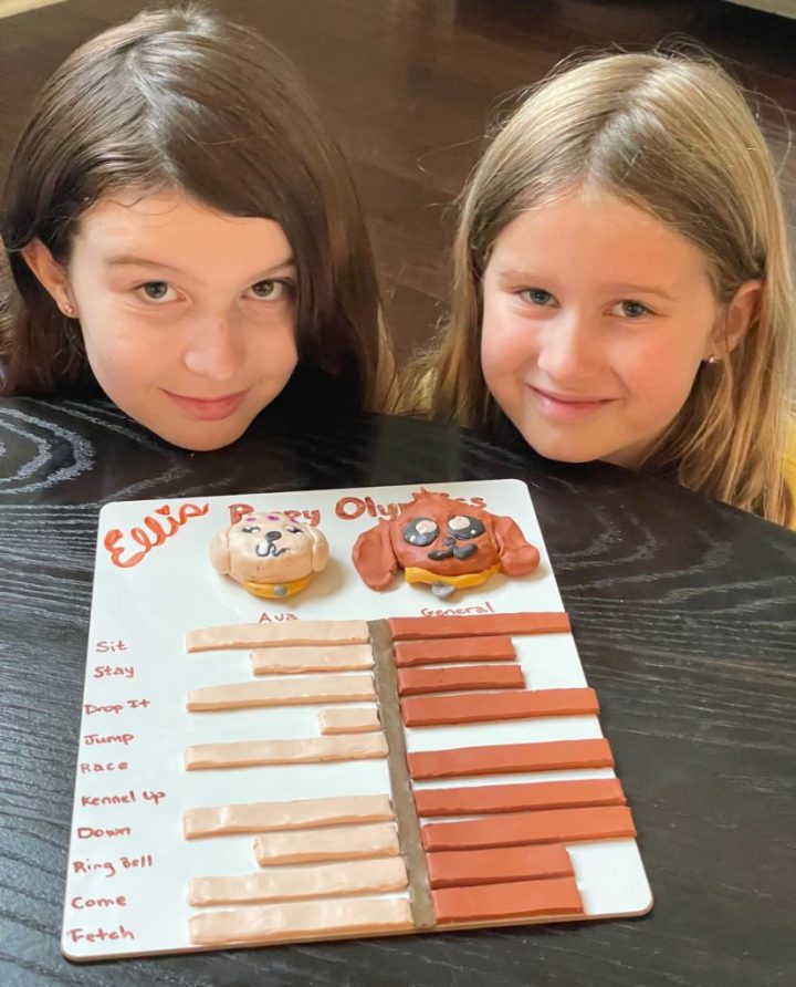 Two young girls pose with their chart made out of clay
