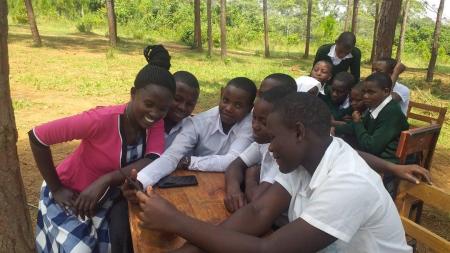 A group of students outside sitting around a table looking at smartphones.