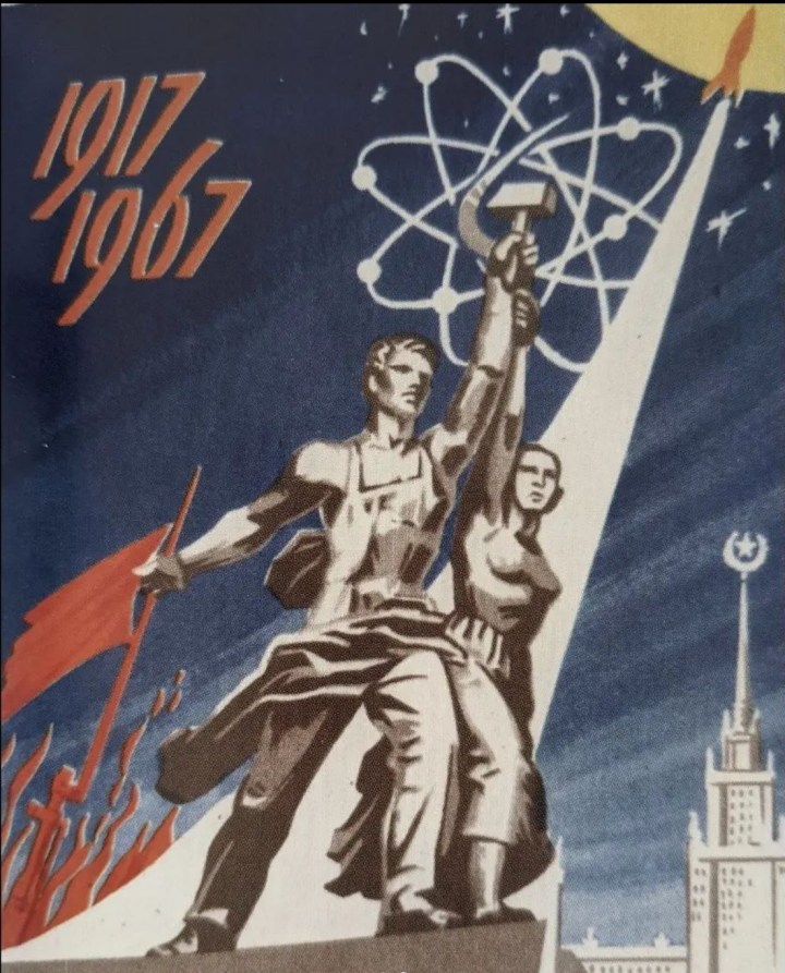 A Soviet Postcard depicting a man and a woman holding aloft a hammer and cycle surrounded by the shape of an atom.  Behind them a rocket takes off, its exhaust represented by a triangle below it.  