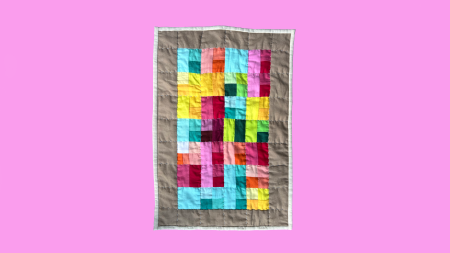 A multicolored quilt sits on a pink digital backdrop