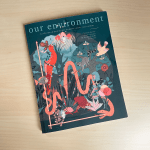 A highly illustrated book cover sitting on a wooden table with the title "our environment"