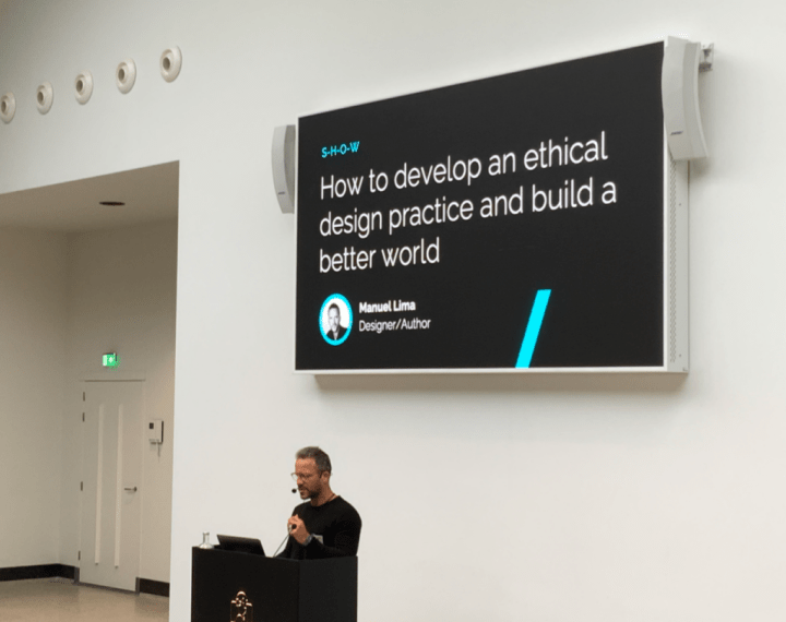 A photo of Manuel Lima at the lectern. The screen behind him says "How to develop an ethical design practice and build a better world."
