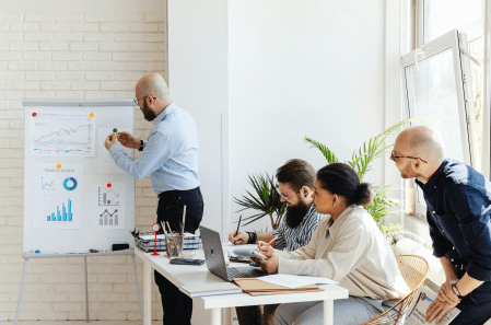 a man gives a presentation of charts and graphs to a room of people.