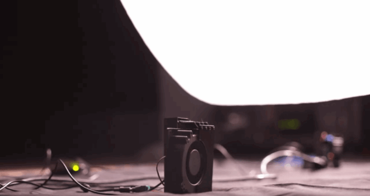 A photo of a black fan under a white sheet.